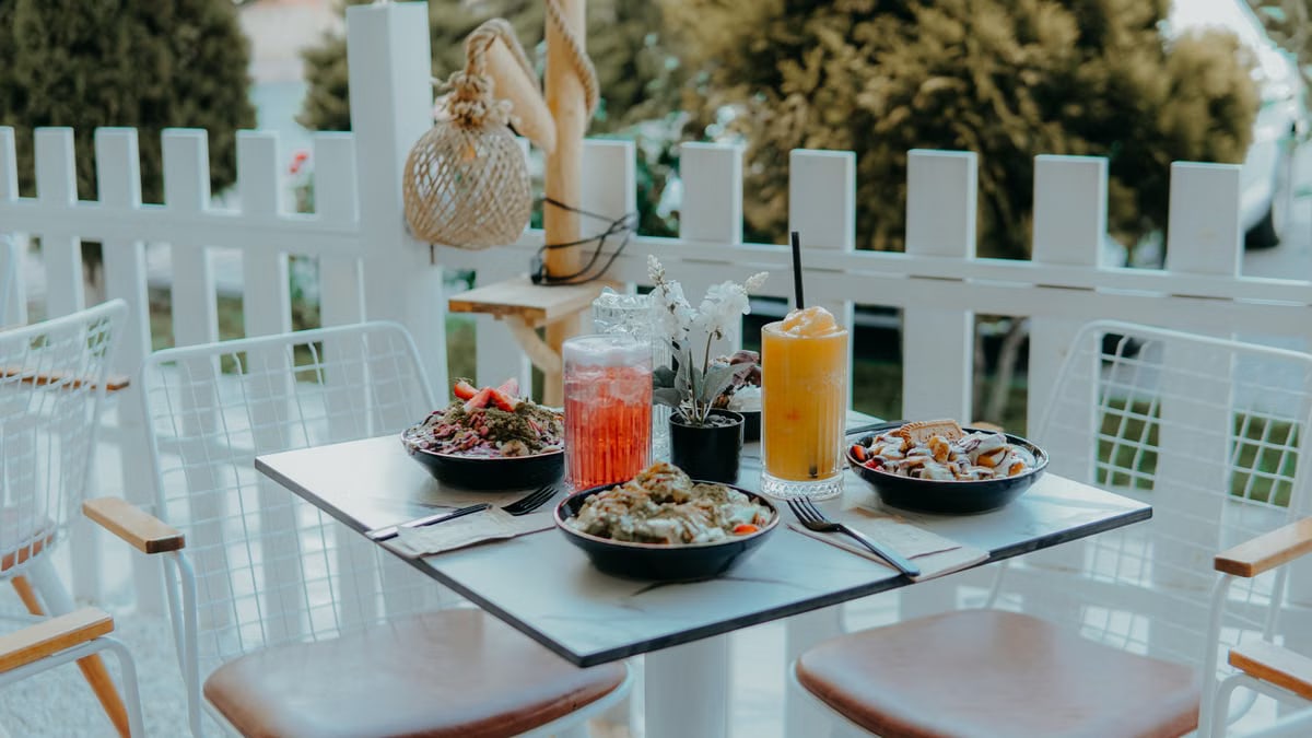 A cozy outdoor cafe table with colorful salads, refreshing drinks, and a serene garden view.